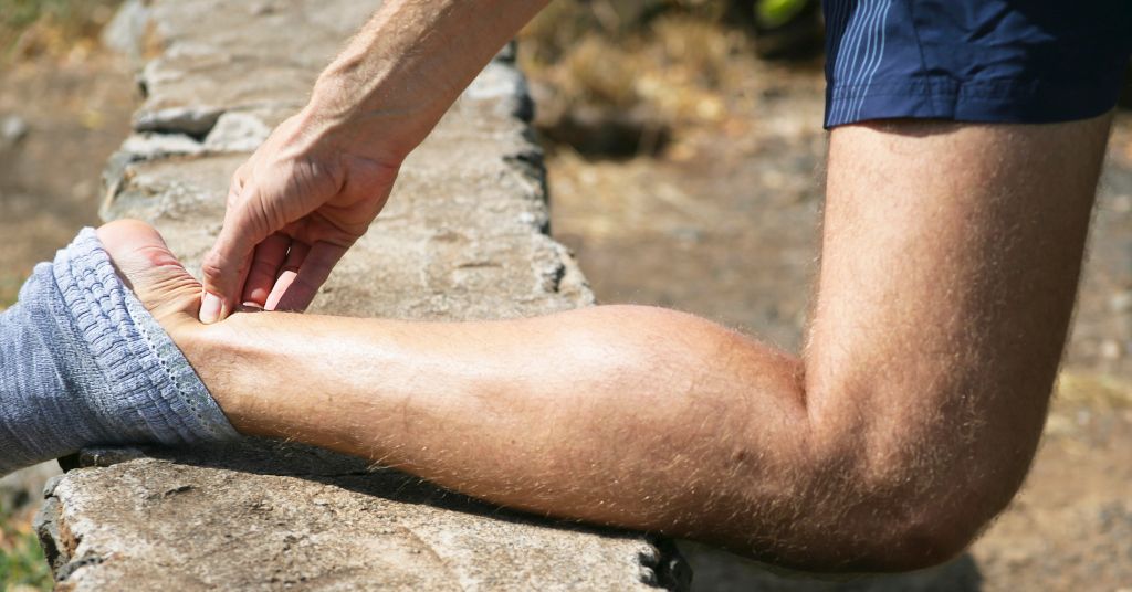 Das Foto zeigt einen Sportler der sich den schmerzenden Fuß hält als Sinnbild für eine Linderung durch die Faszientherapie beim Achillessehnenschmerz