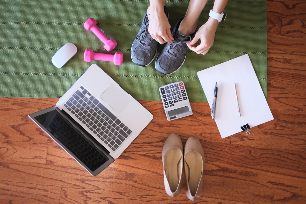 Das Foto symbolisiert mit Laptop, Taschenrechner und Notizblock sowie Turnschuhen und Fitnesshanteln die durch betriebliches Gesundheitsmanagement ermöglichte Work-Life-Balance