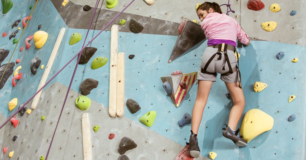 Das Bild zeigt eine Jugendliche beim Klettern an einer Kletterwand als Beispiel einer Physiotherapie-Einheit hier im Beitrag Therapeutisches Klettern