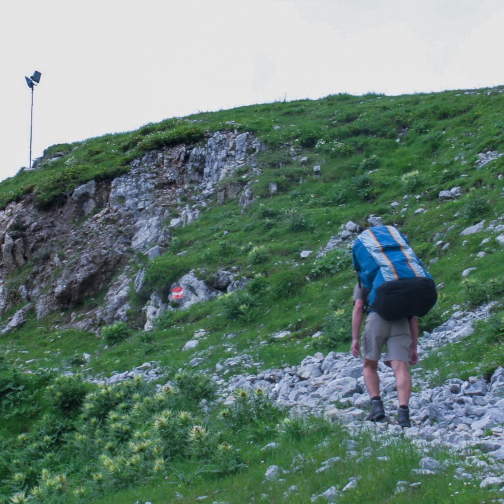 Das Foto zeigt den Autor beim Aufstieg auf den Berg mit seinem Equipment im Rucksack als Beispiel in seinem Erfahrungsbericht mit Tipps damit du wegen Beschwerden nicht dein Hobby oder den Sport aufgeben musst