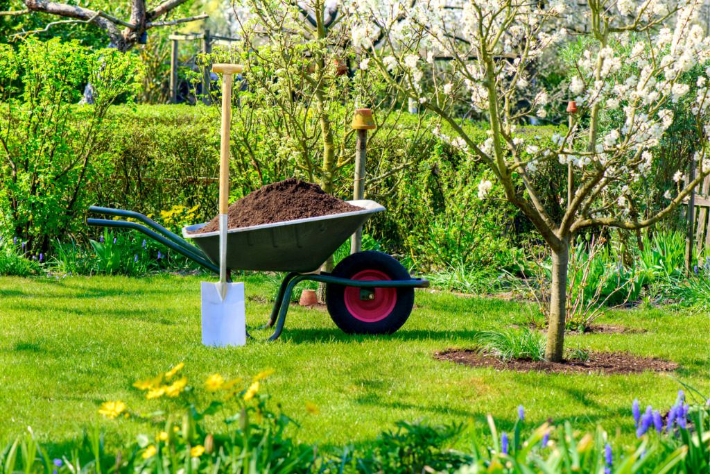 Das Bild zeigt eine Schubkarre voll mit Erde als Beispiel für die schonende Bewegung bei der Gartenarbeit mit der richtigen Ausstattung
