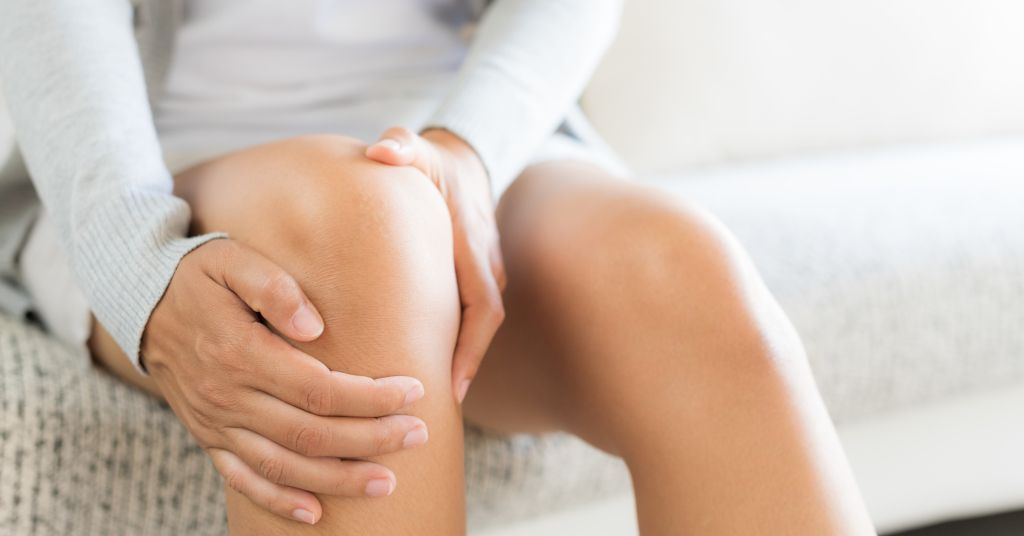Das Foto zeigt eine Nahaufnahme eines Menschen, der sich das schmerzende Knie hält, als Sinnbild für die Bedeutung der richtigen Ernährung gegen Knieschmerzen