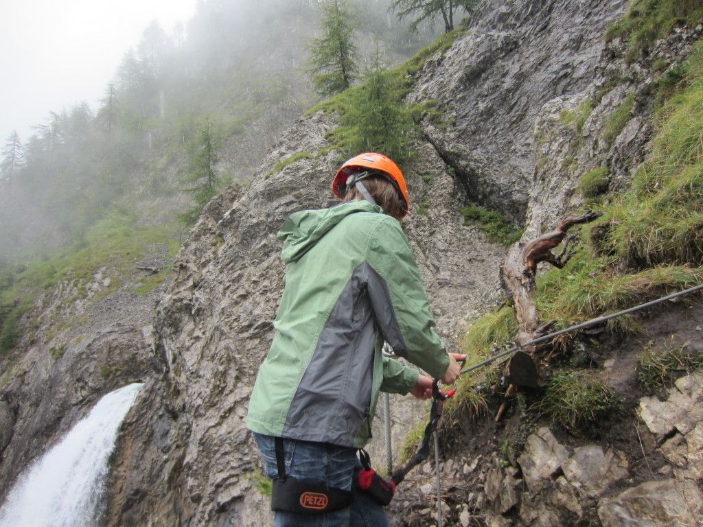 Das Bild zeigt eine Person, die sich am Stahlseil sichert, hier im Beitrag Klettersteige