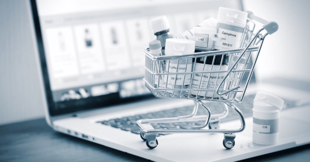 Das Bild zeigt einen kleinen Einkaufswagen mit verschiedenen Medikamenten auf einem Laptop als Sinnbild für die einfache Nutzung der Online Angebote von Apotheken