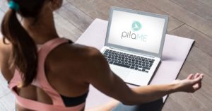 Das Foto zeigt eine Frau auf einer Gymnastikmatte zuhause vor dem Laptop als Sinnbild für den einfachen Zugang zum Online Präventionskurs Pilates