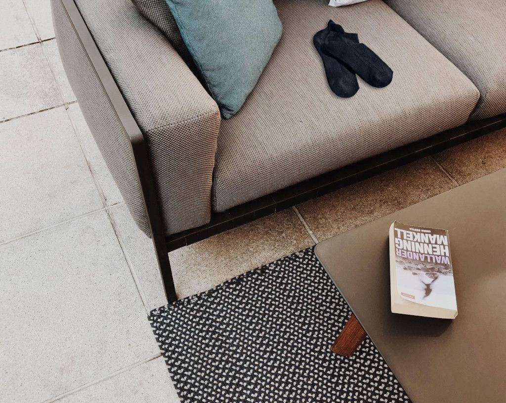 Das Bild zeigt ein Sofa und ein Buch auf dem Tisch als Sinnbild für einen entspannten Tagesausklang hier im Beitrag Progressive Muskelentspannung in einem Kurs lernen