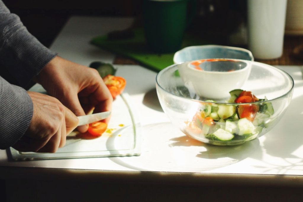 Das Foto zeigt Hände beim Zubereiten von Gemüse in einer Schüssel als Sinnbild für eine Salat Bowl zum Mitnehmen