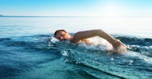 Das Foot zeigt einen Mann beim Schwimmen im warmen Meer mit Sonnenschein
