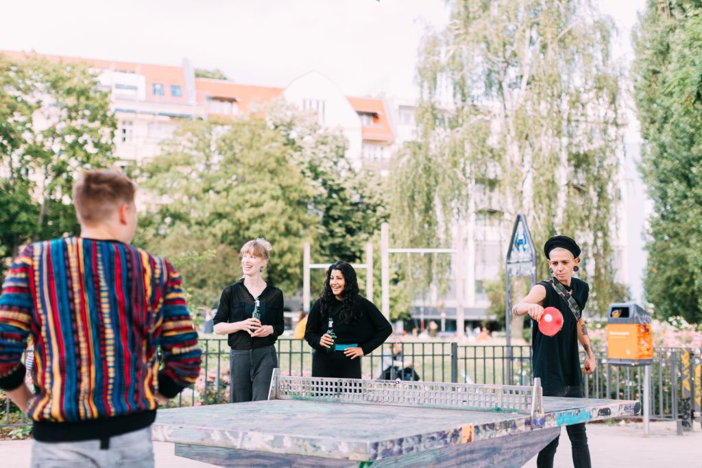 Das Foto zeigt junge Menschen beim geselligen Tischtennis spielen im Freien