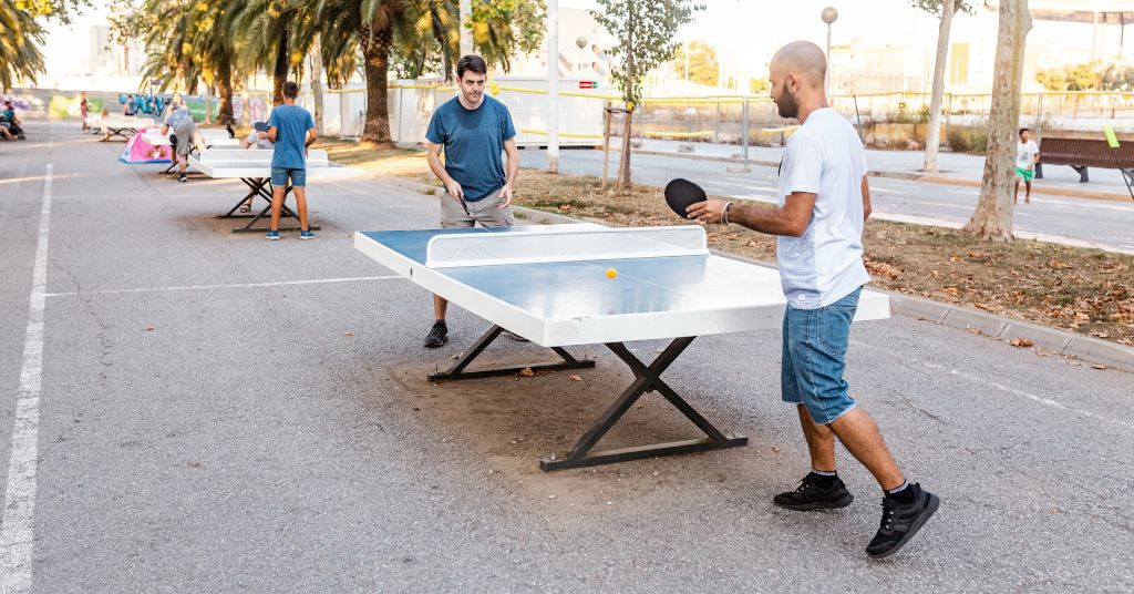 Das Foto zeigt zwei Menschen, die auf einer öffentlichen Platte Tischtennis spielen