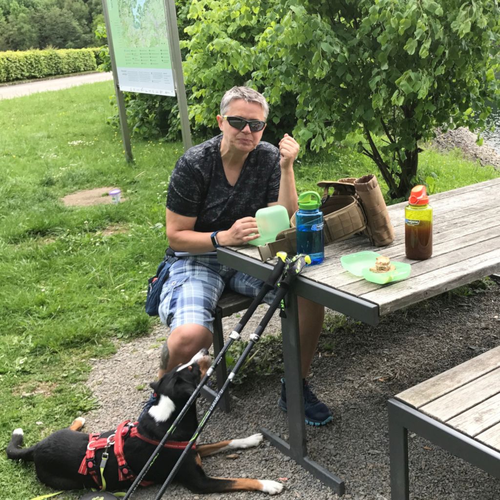 Das Foto zeigt die Autorin Ulla Schaffrath bei der Rast um sich und ihrem Hund eine entspannende Pause beim Outdoorsport Wandern zu gönnen