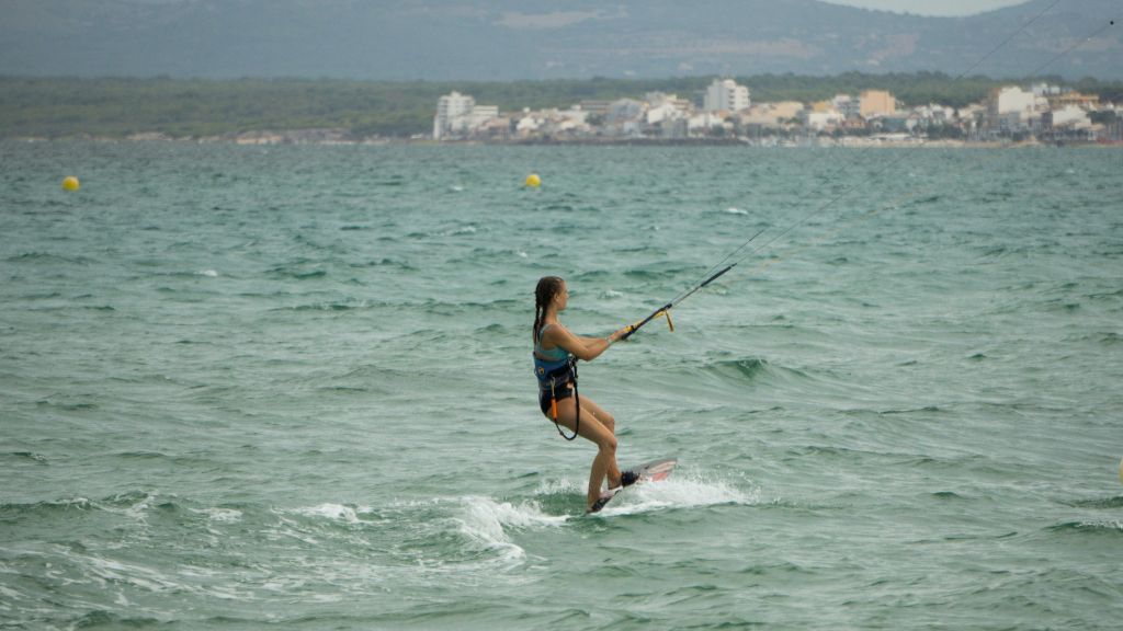 Das Foto zeigt eine Jugendliche beim Kitesurfen im warmen Mittelmeer