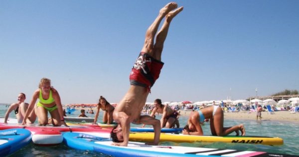 Das Bild zeigt viele Menschen bei SUP Yoga Übungen als Sinnbild für die Beantwortung typischer Fragen rund um den Trendsport.