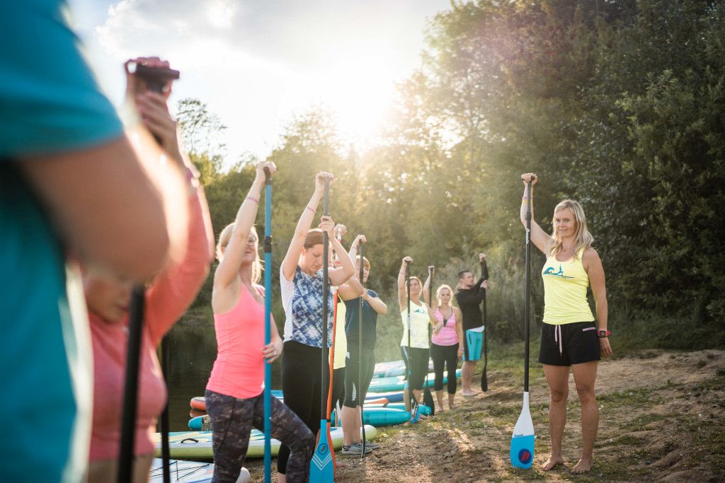 Das Bild zeigt eine Gruppe von Julia Klesse bei der Einweisung vor dem SUP Yoga.