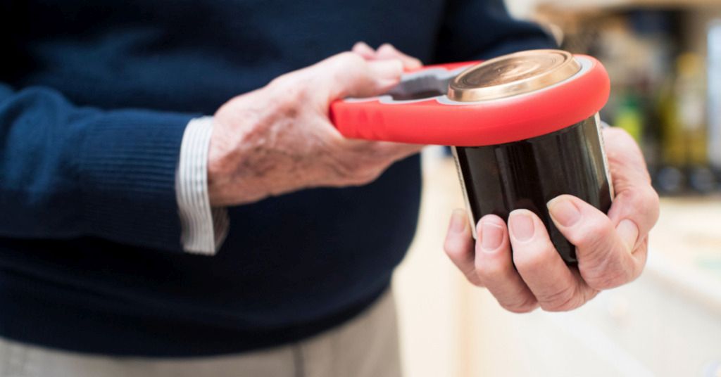 Das Bild zeigt einen Senioren beim Öffnen eines Glases mit Hilfsmittel als Sinnbild dafür wir ergonomische Arbeitsmittel helfen können, die Belastung der Hand zu reduzieren