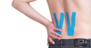 Das Bild zeigt einen nackten Rücken mit aufgeklebten Tape-Streifen als Sinnbild für die Linderung durch Kinesio-Tapes bei Beschwerden am Rücken