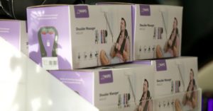 Das Bild zeigt einen Stapel von Packungen mit dem Bild eines elektrische Massagegerätes für den Nacken als Sinnbild für die wirksame Massage zuhause mit dem passenden Massagegerät