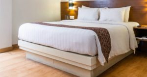 Das Bid zeigt ein gemachtes Bett im Schlafzimmer mit dicker Matratze als Sinnbild für einen entspannten und erholsamen Schlaf mit der richtigen Ausstattung