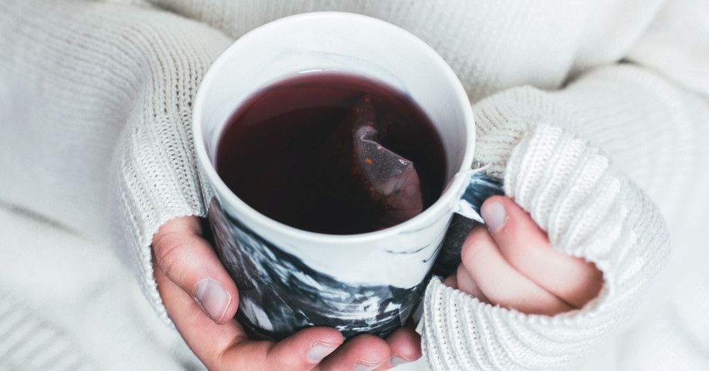 Das Bild zeigt zwei Hände die eine Tasse Tee halten als Sinnbild für die Möglichkeit, mit der richtigen Vorbereitung am Abend die Muskeln zu entspannen und besser zu schlafen