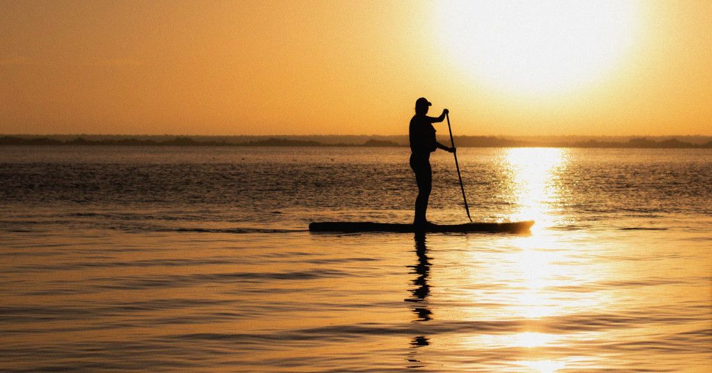 Das Bild zeigt einen Menschen beim genüsslichen Stand Up Paddling im Sonnenuntergang als Sinnbild für die Auswahl des richtigen Stand Up Paddle Board