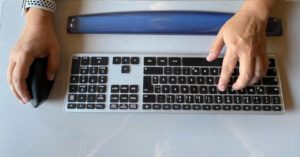 Das Bild zeigt eine zwei Hände bei der Arbeit am Computer mit ergonomischer Maus, Tastatur und Handgelenkauflage als Sinnbild für die Entlastung der Hände und Arme durch ergonomische Arbeitsmittel im Büro