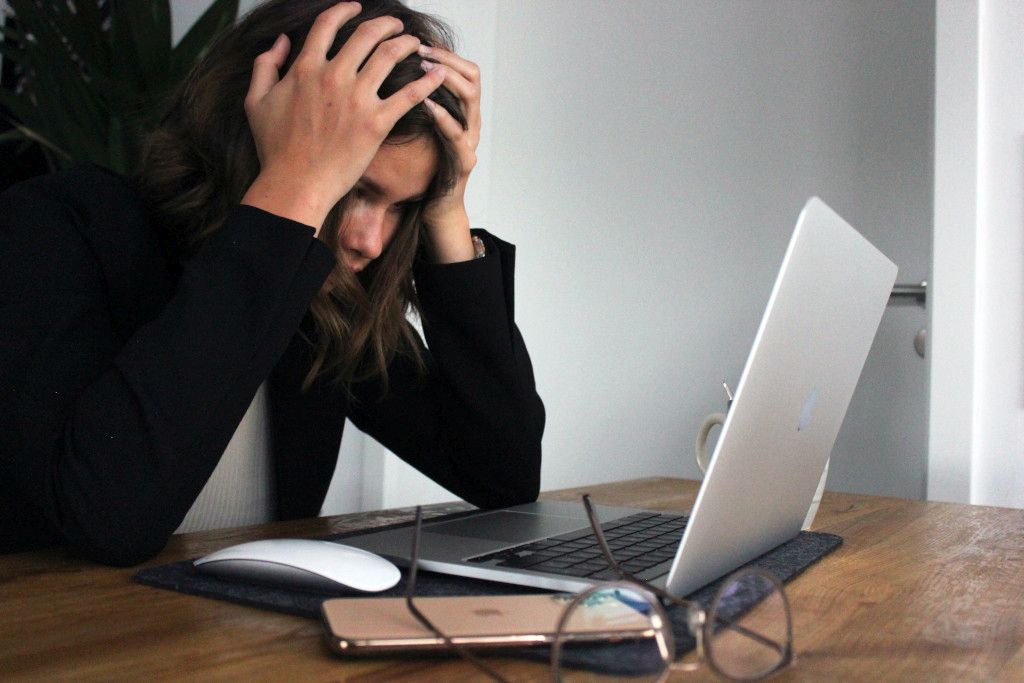 Das Bild zeigt einen verzweifelten Menschen vor dem Laptop als Sinnbild für den heutigen Stress und die Belastungen am Arbeitsplatz die unsere mentale Balance stören