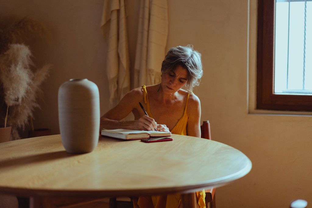 Das Bild zeigt einen Menschen beim Notieren am Esstisch als Sinnbild für den Beitrag der Dokumentation des eigenen Verhaltens bei der Stressbewältigung