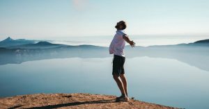 Das Bild zeigt einen Mann auf einer Bergspitze über den Wolken als Sinnbild für das Thema Stressmanagement im Onlinekurs erlernen um wirksam Stress zu reduzieren und gelassener zu werden