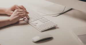 Das Bild zeigt zwei Hände in einer unnatürlichen Haltung bei der Arbeit mit einer Tastatur als Sinnbild für den Beitrag der Faszientherapie zur Behandlung von Handgelenkschmerzen