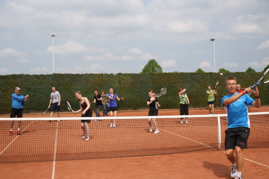 Das Bild zeigt eine Gruppe von Kursteilnehmern auf einem Tennisplatz als Sinnbild für die Gemeinschaft beim Tennis als Gesundheitssport