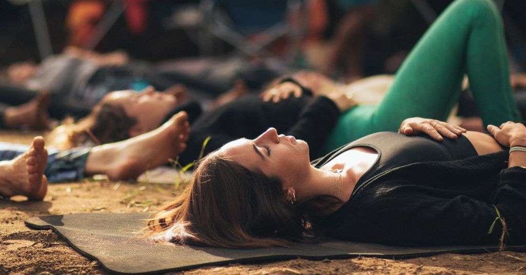 Das Bild zeigt Menschen beim gemeinsamen Entspannen auf einer Yogamatte am Strand als Sinnbild für die Reinigung und Entgiftung von Körper, Geist und Seele beim Body and Mind Clearing