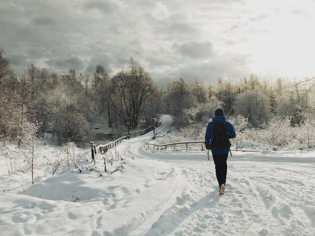 Das Bild zeigt einen Menschen beim Wandern im Schnee als Sinnbild für schönen und gesunden Sport in der Kälte