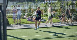 Das Bild zeigt eine Frau beim Outdoor Padel Tennis als Sinnbild für Padel und Paddle Tennis als den neuen Trendsportarten im Tennissport