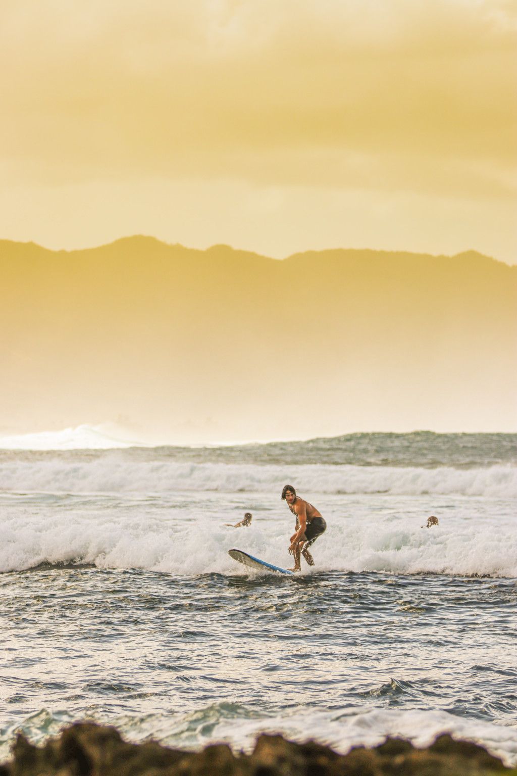 Das Bild zeigt einen Surfer im Meer vor Hawaii als Sinnbild für den Spirit of Aloha