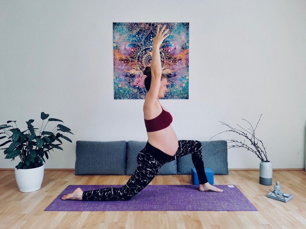 Das Bild zeigt die schwangere Trainerin beim Yoga im Wohnzimmer für eine bessere Balance als Sinnbild für die Unterstützung in der Schwangerschaft durch Schwangerschaftsyoga im Online Kurs