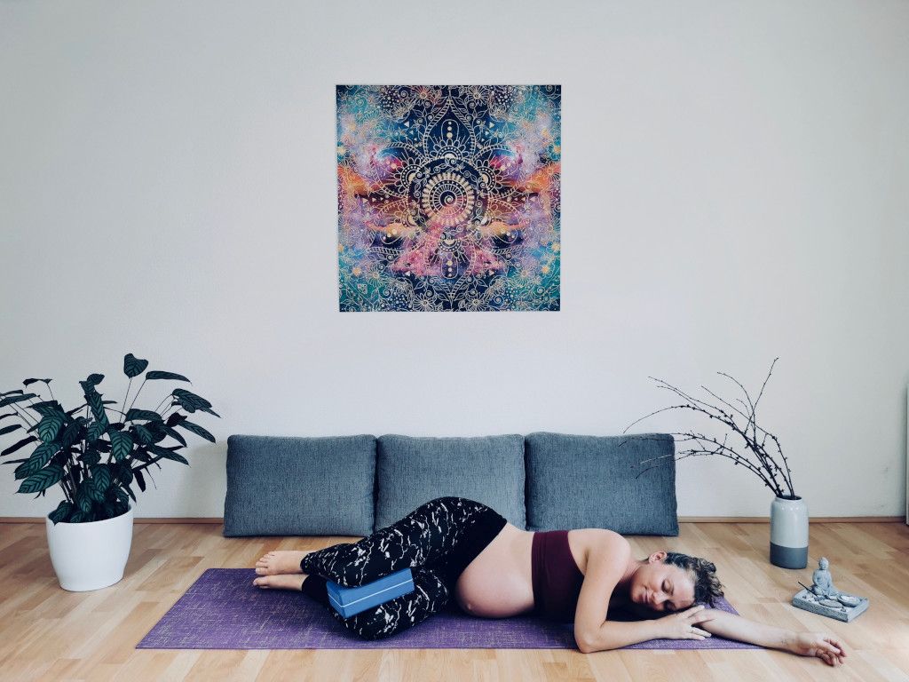 Das Bild zeigt die schwangere Trainerin bei der Entspannung im Wohnzimmer als Sinnbild für mehr Ruhe und Gelassenheit in der Schwangerschaft durch Schwangerschaftsyoga im Online Kurs