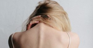 Das Bild zeigt einen leidenden Menschen mit den Händen im Nacken als Sinnbild für die Beschwerden bei Nackenschmerzen und die mögliche Hilfe durch die Faszientherapie