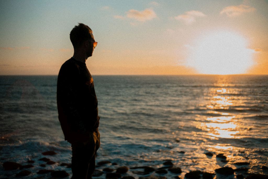 Das Bild zeigt einen Menschen im Sonnenuntergang am Strand als Sinnbild für die Bedeutung der Sinne auf deinem Abnehm-Weg