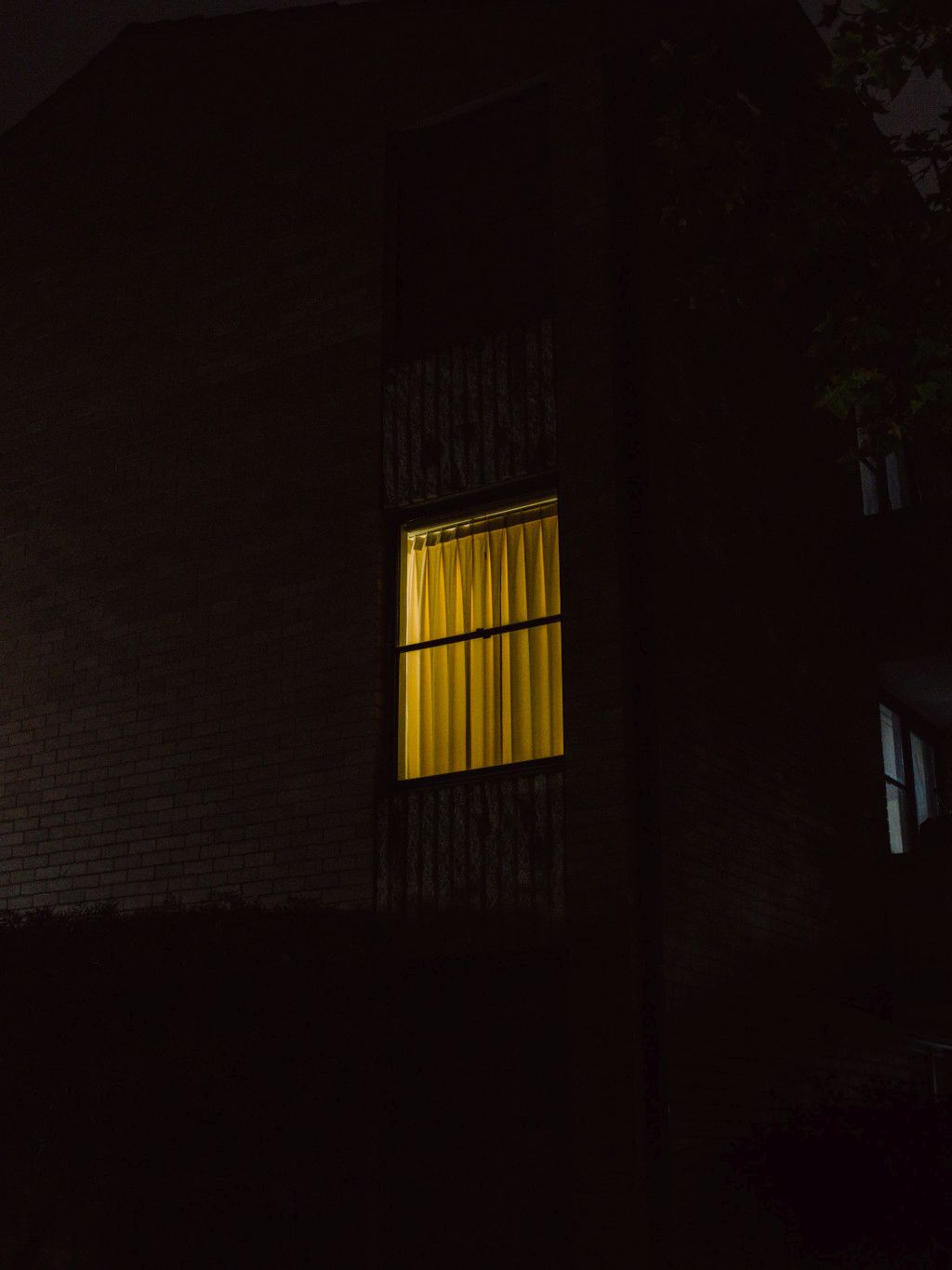 Das Bild zeigt ein Fenster mit Licht in der Nacht als Sinnbild für die Bedeutung von Schlaf zur Regeneration und zum Stressmanagement auf deinem Abnehm-Weg