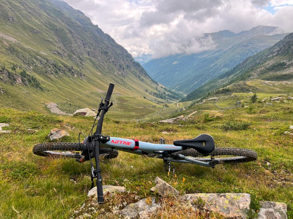 Das Bild zeigt ein Mountainbike vor einer Schlucht in den Alpen als Sinnbild für die vielen Eindrücke die eine geführte Transalp-Tour bietet