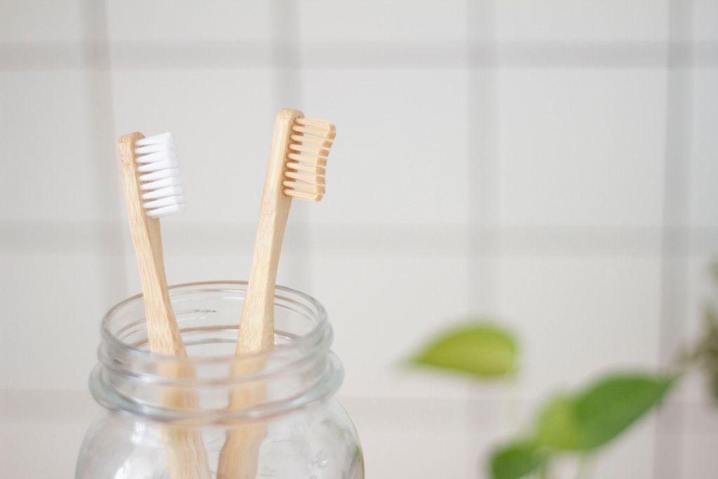 Das Bild zeigt zwei nachhaltige Zahnbürsten aus Bambus in einem Glas als Sinnbild für die richtigen Pflegeprodukte zur Erreichung der besten Zahngesundheit
