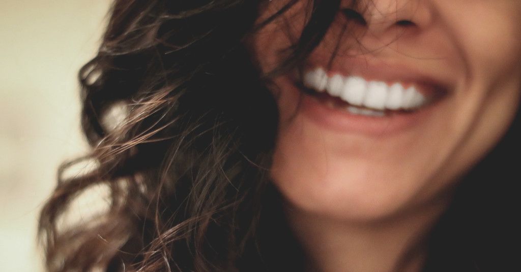Das Bild zeigt ein strahlendes Lächeln mit weißen Zähnen im Gesicht eines glücklichen Menschen als Sinnbild für die Bedeutung der Zahngesundheit für Vitalität und Wohlbefinden.