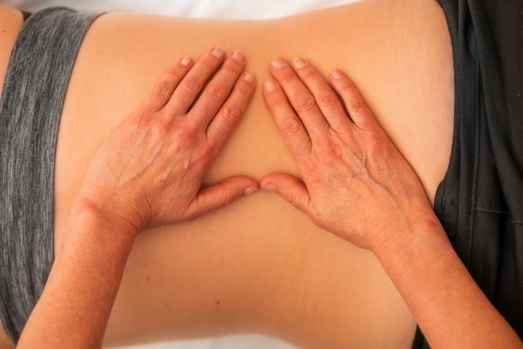 Das Bild zeigt die manuelle Behandlung eines Rückens durch die aufgelegten Hände eines Therapeuten als Sinnbild für die Wirkung der Physiotherapie und der Osteopathie bei unspezifischen Rückenschmerzen