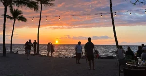 Das Bild zeigt glückliche Menschen an einem hawaiianischen Traumstrand im Sonnenuntergang als Sinnbild für Aloha und Ohana und die Kraft der Huna-Lehre aus Hawaii, die du auch im Märchenhaus Mannheim entdecken und erleben kannst.