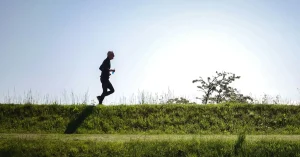 Das Bild zeigt einen Mann beim Slow Jogging auf einer grünen Wiese.