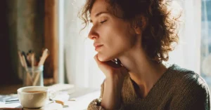 Das Bild zeigt eine erschöpfte Frau am Tisch mit einer Tasse Tee als Sinnbild dafür, dass ständige Müdigkeit und Hashimoto zusammenhängen können und wie Du Deine Hormone und Dein Wohlbefinden wieder in das Gleichgewicht bringst.
